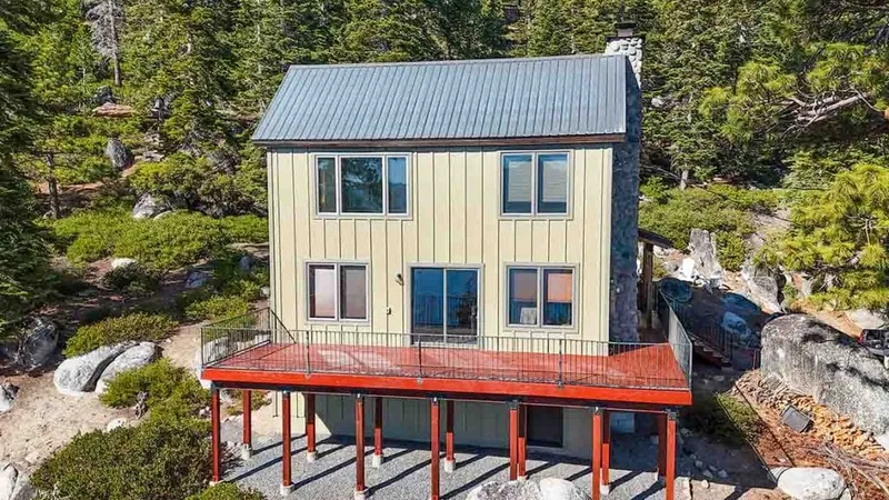 Two-storey board-and-batten house in a pine stand with slim-profile window frames on the gable and main floor elevations