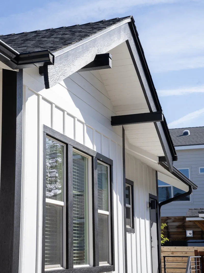 Black-trimmed double-hung windows and a board-and-batten corner detail