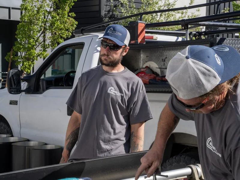 Two crew members conferring over the work table beside the truck