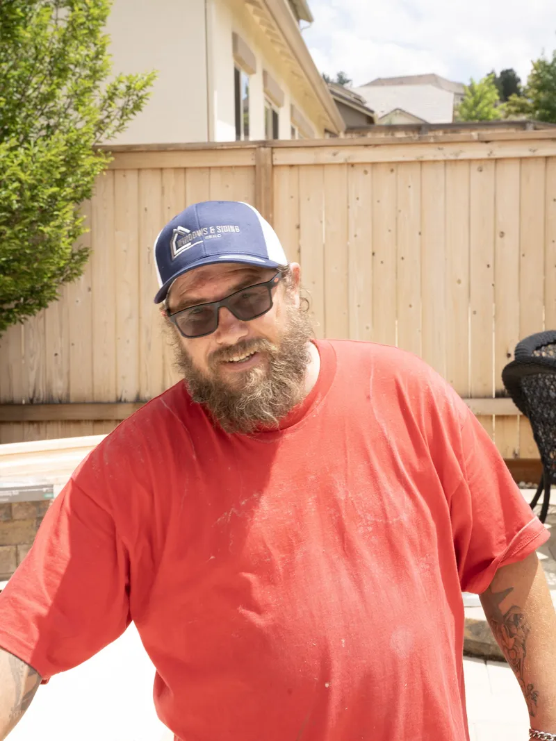 Smiling crew member in a branded cap on a job site