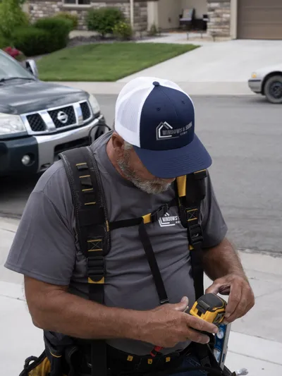 Crew member in a branded cap checking his tape measure
