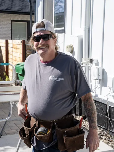 Crew member in a Windows and Siding Reno shirt and tool belt on a job site