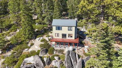 Aerial view of a board-and-batten house with new windows on a granite ridge above Lake Tahoe