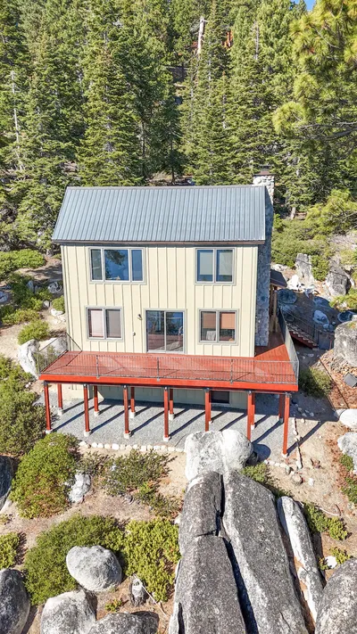Drone view of the front of a board-and-batten house with new dual-pane windows above Lake Tahoe