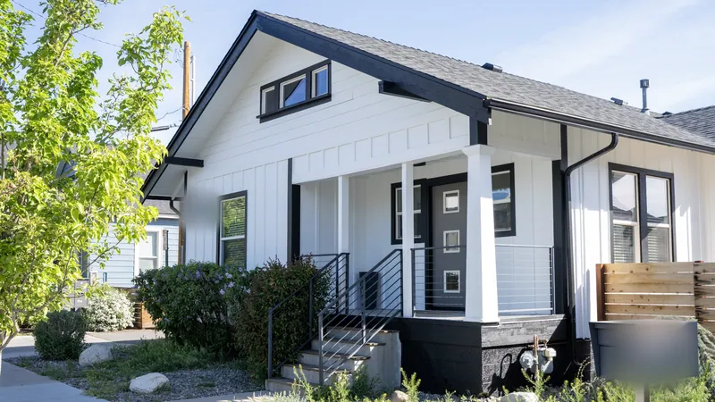 White board-and-batten bungalow with black trim, a covered porch and a dark entry door on a Northern Nevada street