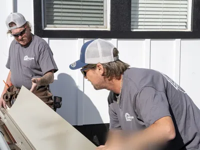Two crew members in branded shirts handling a trim sheet together at the brake