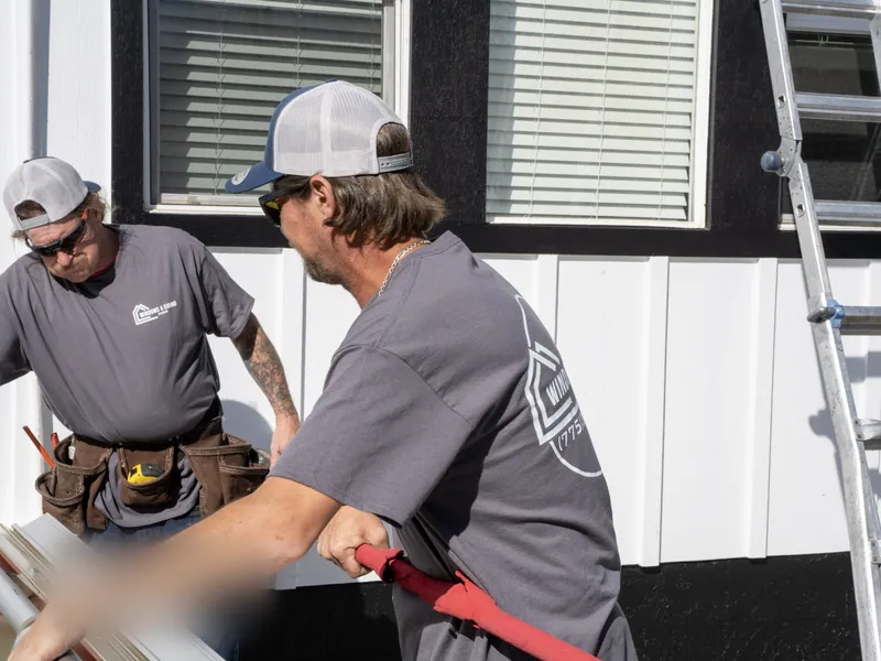 Two of our crew forming a white window trim piece on a portable brake