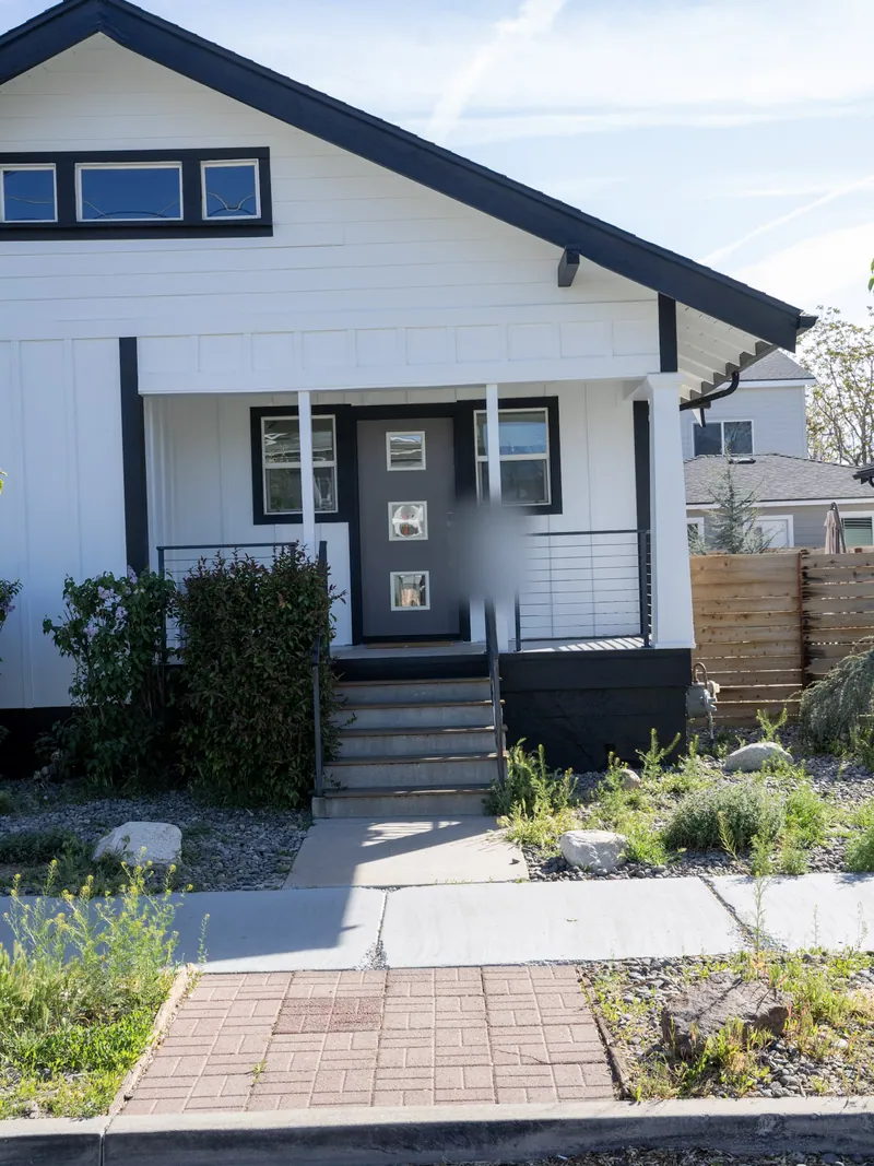 Front entry with a grey door, transom glass and covered porch after replacement