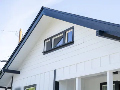 Gable end with a black-trimmed triple awning window and board-and-batten siding