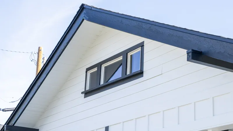 Gable end with a black-trimmed triple awning window and board-and-batten siding