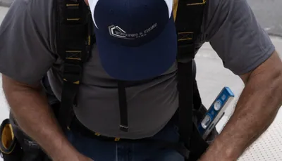 Overhead view of a Windows and Siding Reno installer in a logo cap and tool belt suspenders, a level at his hip
